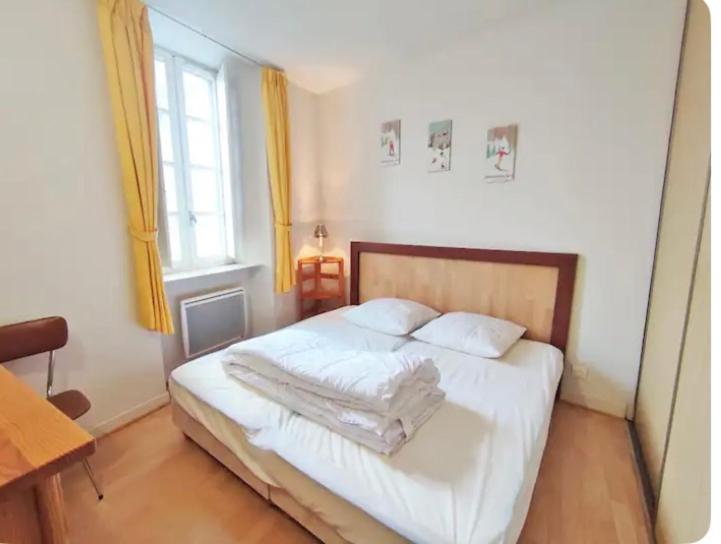 une chambre avec un lit avec des draps blancs et une fenêtre dans l'établissement Logement à proximité des télécabines et en face du parc des thermes, à Luchon