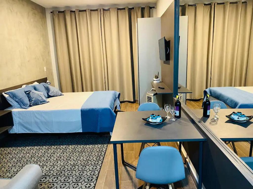 a hotel room with two beds and a table and chairs at Flat Aconchegante 1 in Sorocaba
