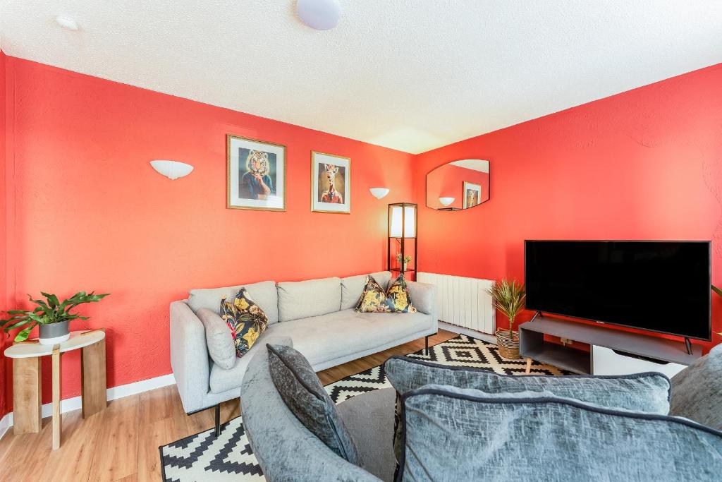a red living room with a couch and a tv at Spacious 2-Bedroom Main Door Apartment With Private Parking in Glasgow