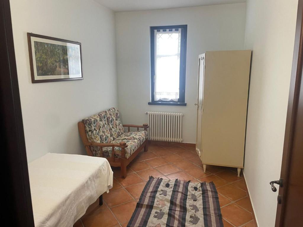 een kamer met een bed, een stoel en een koelkast bij Casa Gatti: villa con giardino con accesso indipendente in Rivanazzano