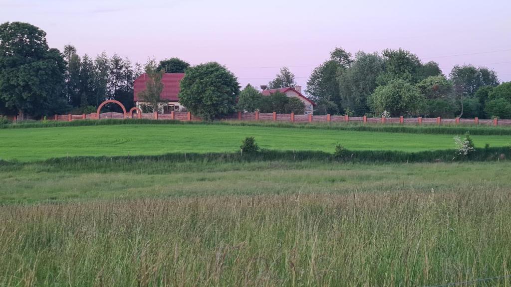 un gran campo verde con un granero en el fondo en Mazurskie Uroczysko, en Stręgielek