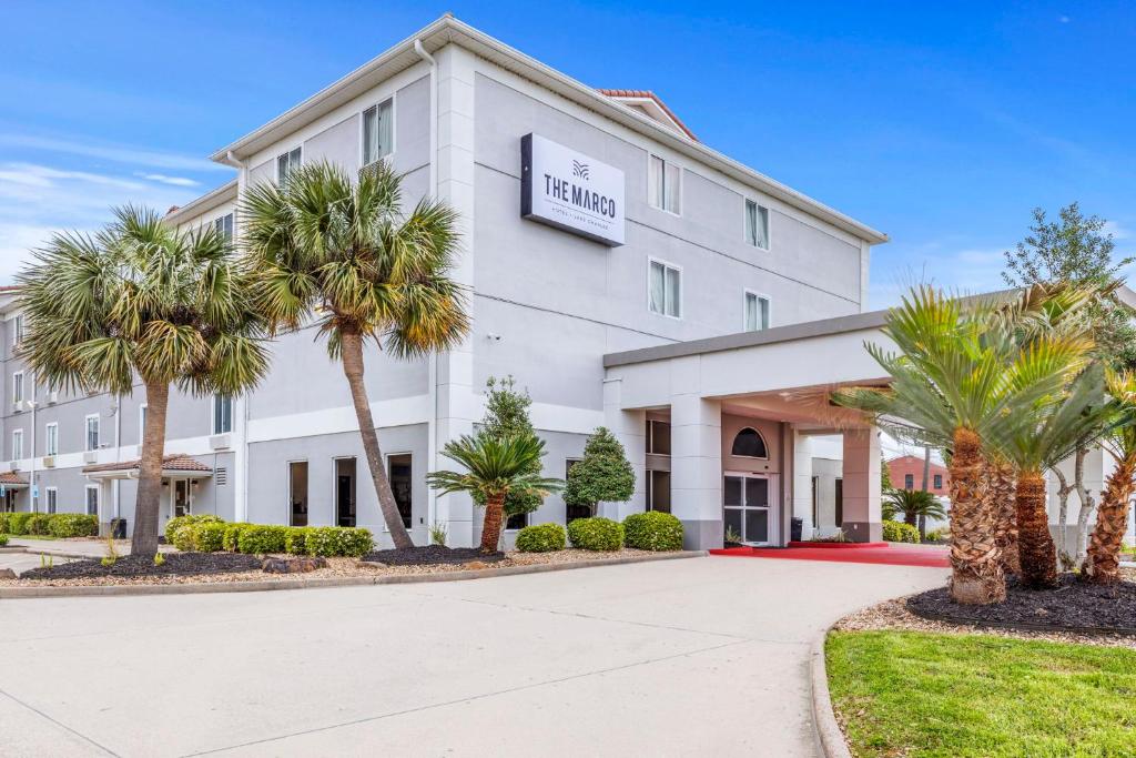 a hotel with palm trees in front of a building at The Marco Hotel Lake Charles in Lake Charles