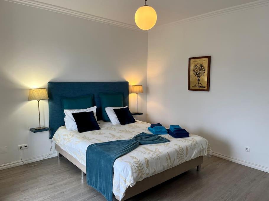 a bedroom with a large bed with a blue headboard at Caloura Water Accommodation in Lagoa