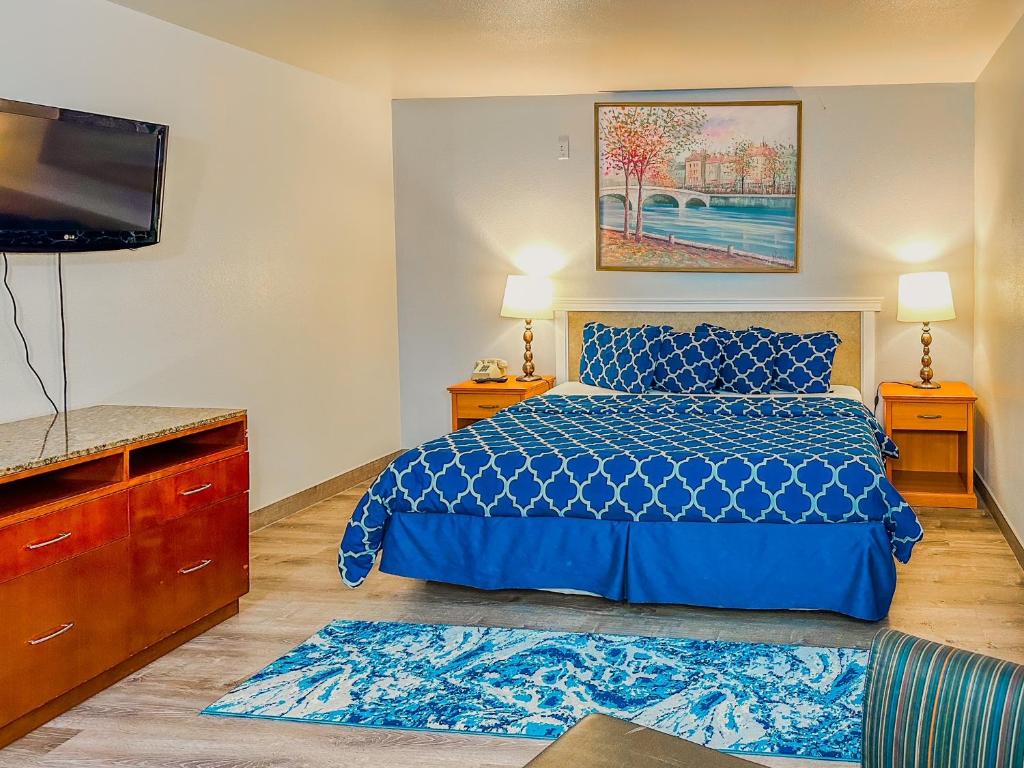 a bedroom with a blue bed and a flat screen tv at Americas Inn & Suite in Shoreline