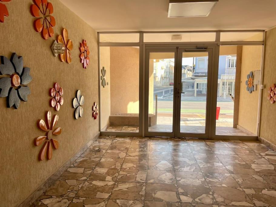 un couloir vide avec des portes en verre et des fleurs sur le mur dans l'établissement Studio Ti’Sable 50m de la plage, à Fort-Mahon-Plage