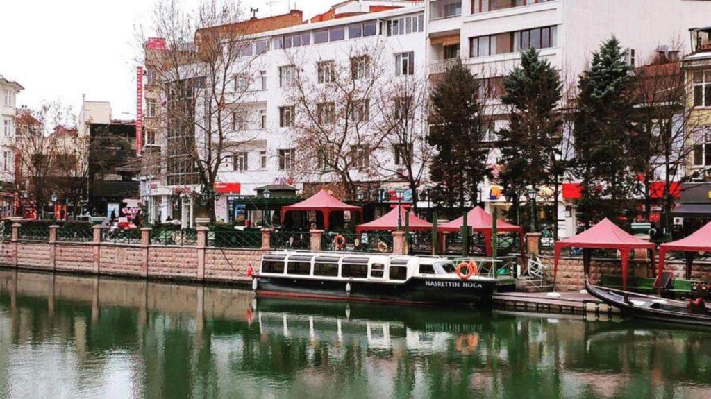 a boat is docked next to a river with buildings at Manzara Hotel in Eskisehir