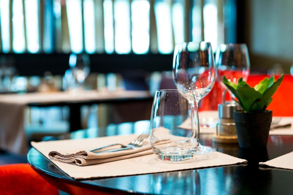 - une table avec deux verres à vin et une serviette dans l'établissement BRIT HOTEL CONFORT Saint-Brieuc Langueux, à Langueux