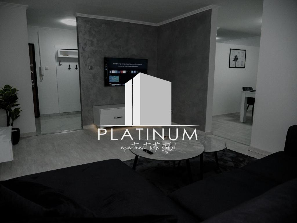 a living room with a table and a white refrigerator at Apartman PLATINUM in Doboj