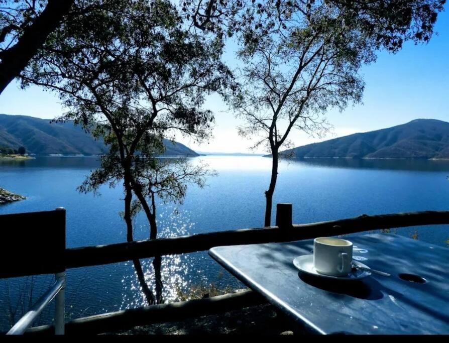 a cup of coffee sitting on a table next to a lake at Cabañas Cabra Corral in Coronel Moldes