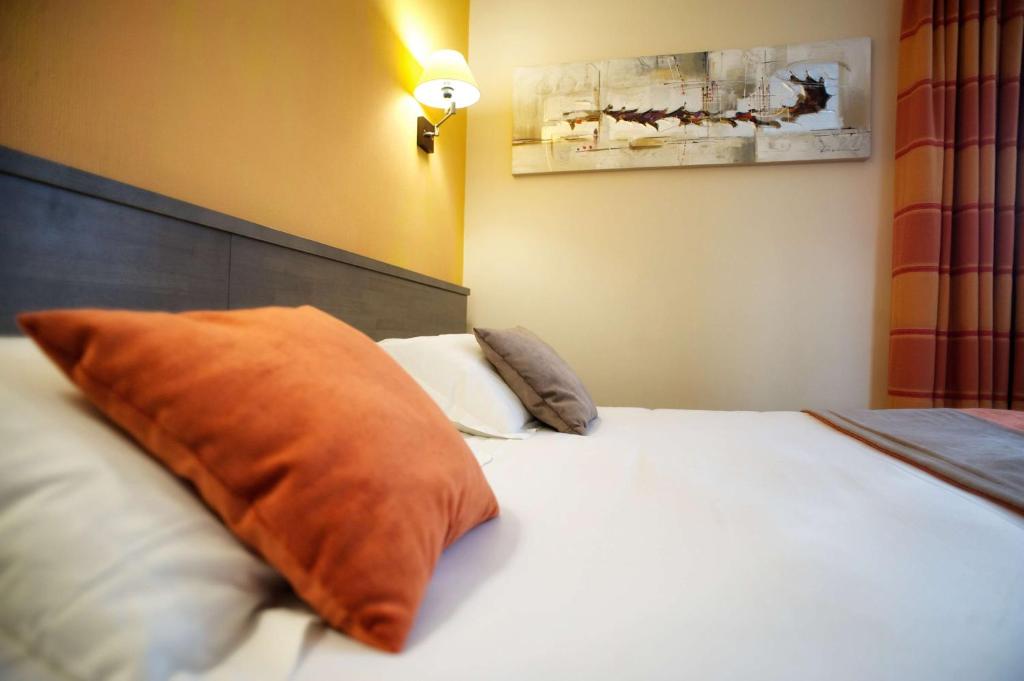 a bedroom with a white bed with two pillows at Brit Hotel Le Surcouf in Saint Malo