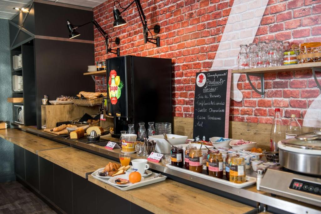 a kitchen with a counter with food on it at Brit Hotel La Rochelle Périgny in Périgny