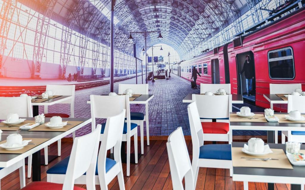 a restaurant with tables and a train station at Brit Hotel de Paris Saint-Jean-de-Luz in Saint-Jean-de-Luz