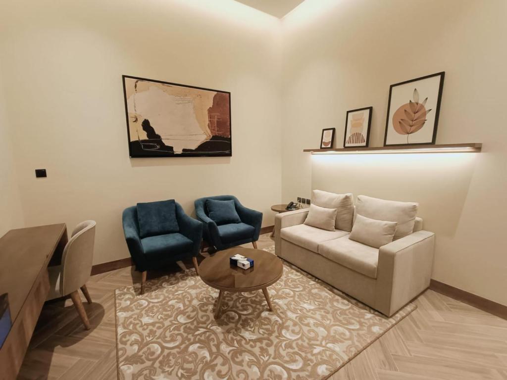 uma sala de estar com um sofá e duas cadeiras em فندق ركايا للشقق الفندقية em Hail