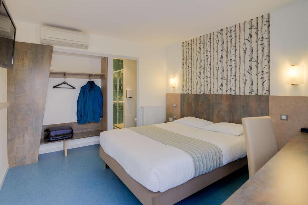 um quarto com uma cama grande e um piso azul em Brit Hotel Hermes em Couchey