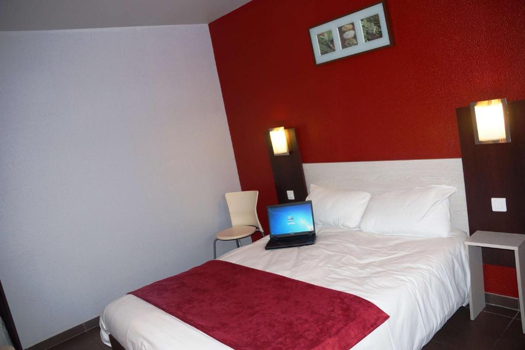 a bedroom with a bed with a laptop on it at Brit Hotel Essentiel Sète / Balaruc in Balaruc-le-Vieux
