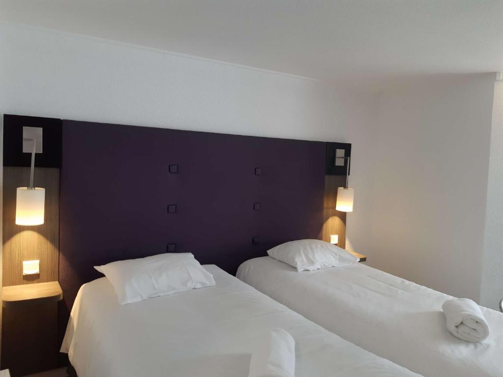 dos camas sentadas una al lado de la otra en un dormitorio en Brit Hotel Reims La Neuvillette, en Reims