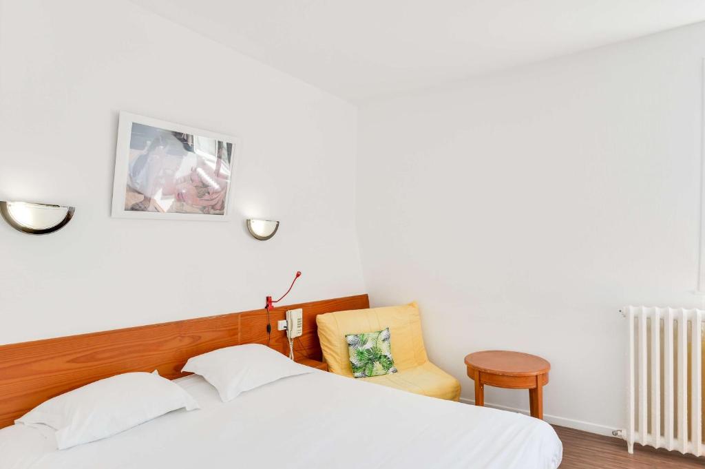 - une chambre avec un lit blanc et une chaise jaune dans l'établissement Brit Hotel Notre Dame, à Valenciennes