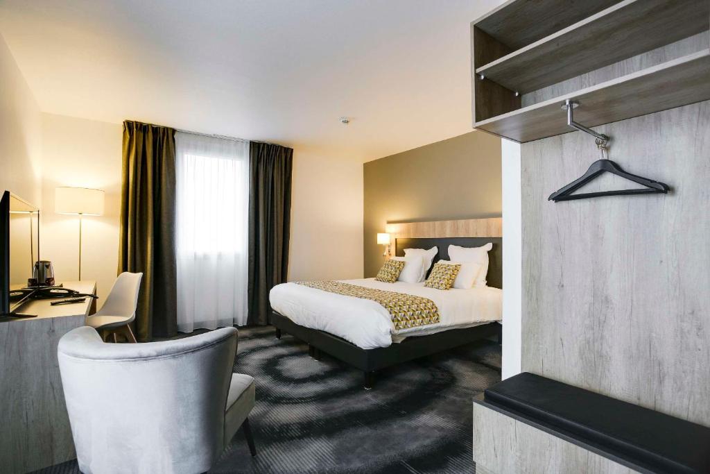 une chambre d'hôtel avec un lit et une chaise dans l'établissement Brit Hotel Confort Loches, à Loches