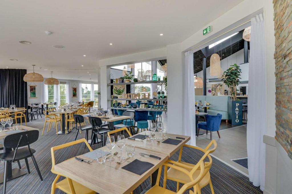 una sala da pranzo con tavoli e sedie e un ristorante di Brit Hotel Au Pays De Vitré a Étrelles