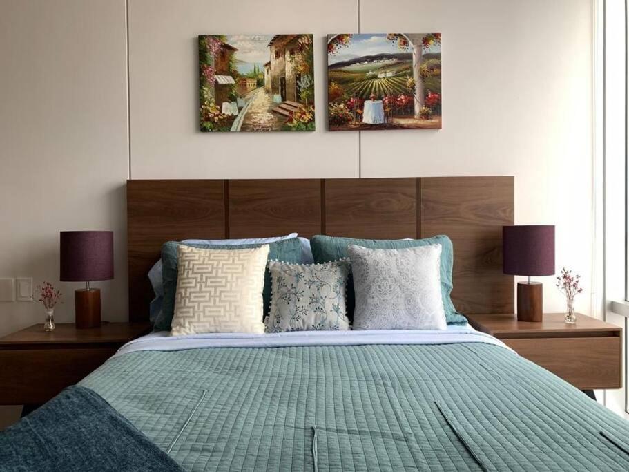 a bedroom with a bed with two paintings on the wall at Olivo Apartment HP - Sur in Mexico City