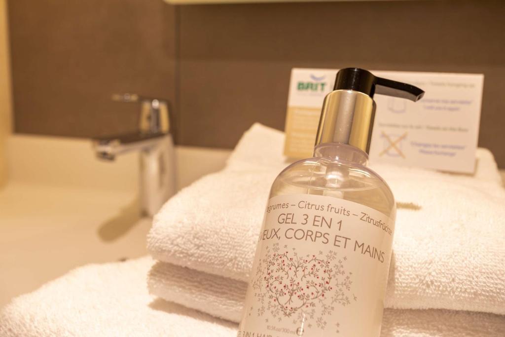 a soap bottle sitting on top of a bathroom sink at Brit Hotel Ploermel - Hotel de l'Hippodrome in Ploërmel