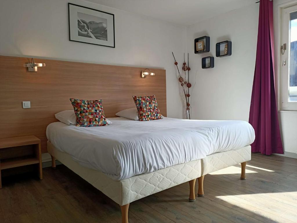 a bedroom with a large bed with a wooden headboard at Brit Hotel Besancon l'Horloge in Besançon