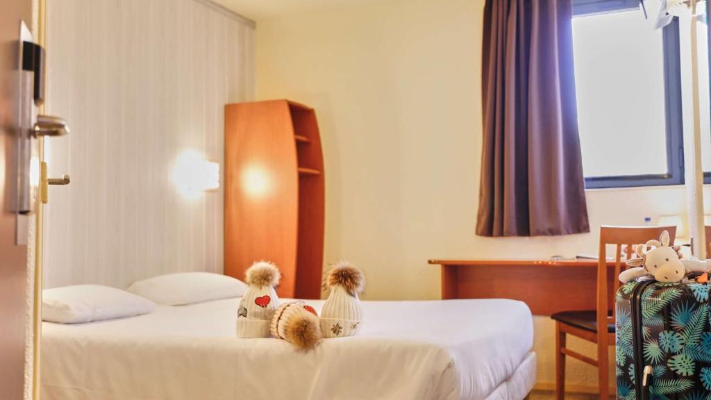 two teddy bears sitting on a bed in a hotel room at Brit Hotel Chambery in Chambéry