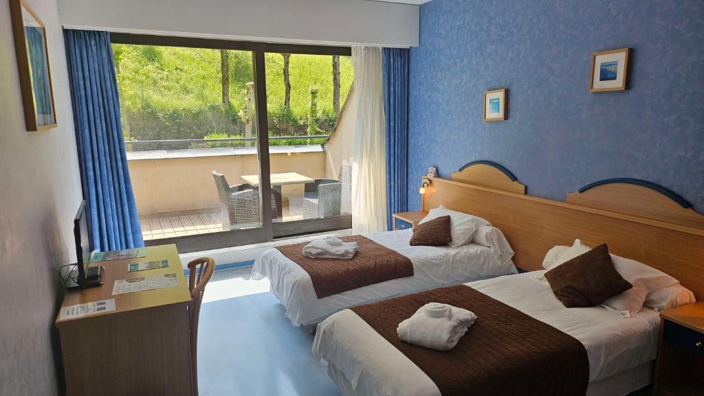 una camera d'albergo con due letti e una finestra di Brit Hotel Du Ban a Chaudes-Aigues