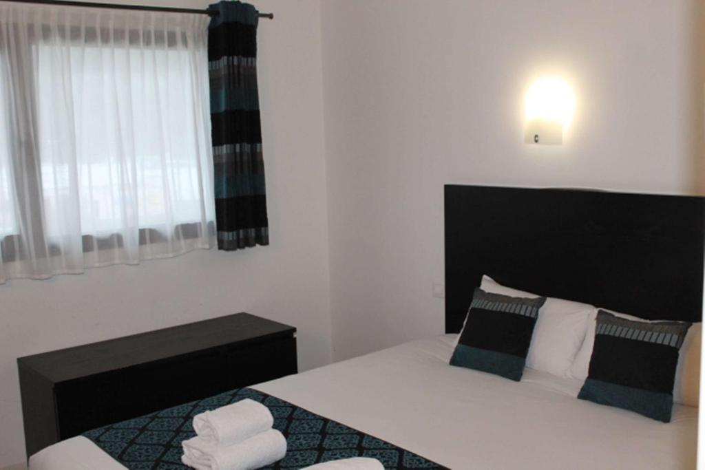 een slaapkamer met een groot wit bed met een zwart hoofdeinde bij Brit Hotel Guinguet' - Lyon L'Arbresle in LʼArbresle