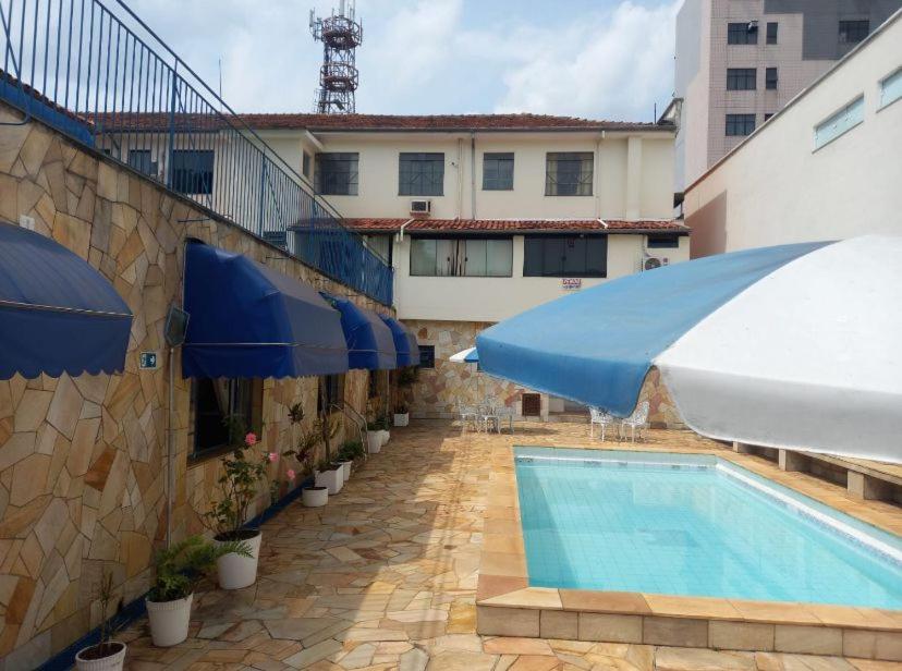 a swimming pool with umbrellas next to a building at Suíte Hotel São José in Caxambu