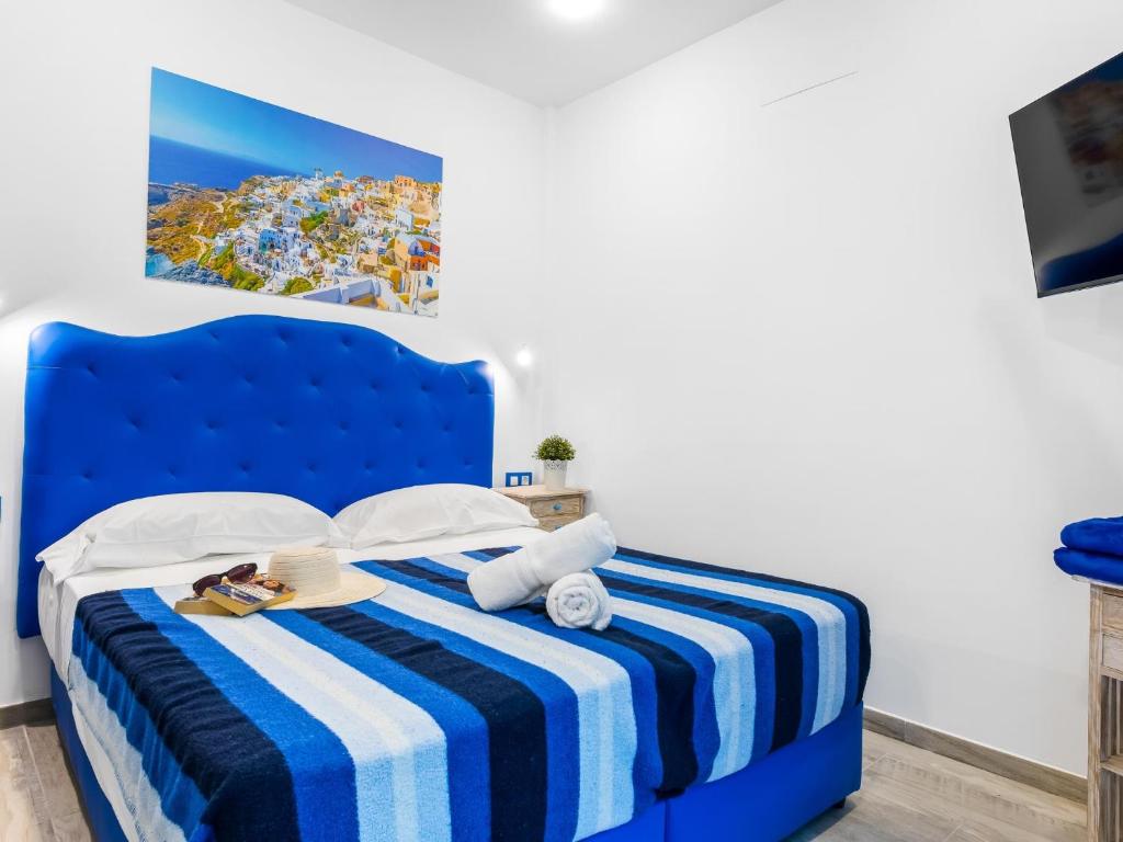 Una cama azul con una manta de rayas azul y blanca en OKEANOS Eco Guest House, en Los Abrigos