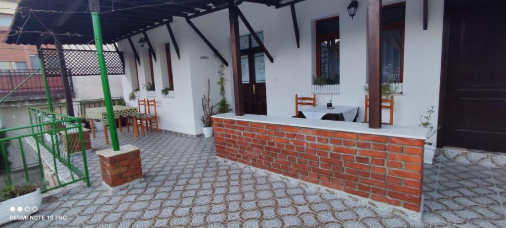 een patio van een huis met een bakstenen muur en een paraplu bij Guest House Baba Lluka in Berat