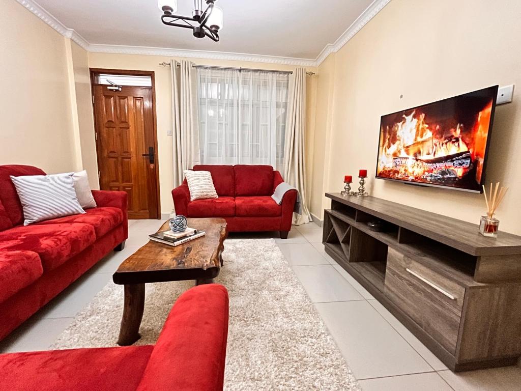 ein Wohnzimmer mit roten Möbeln und einem Flachbild-TV in der Unterkunft Neema Executive Suites Near Junction Mall With Balcony in Nairobi