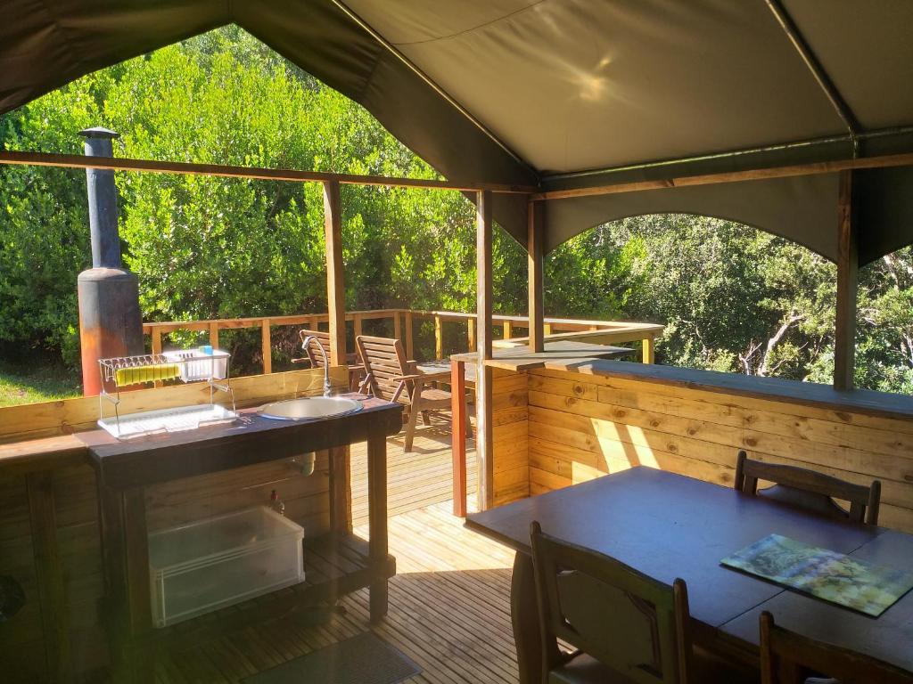 an outdoor deck with a grill and tables and chairs at Wilderness Glamping Tents in Wilderness