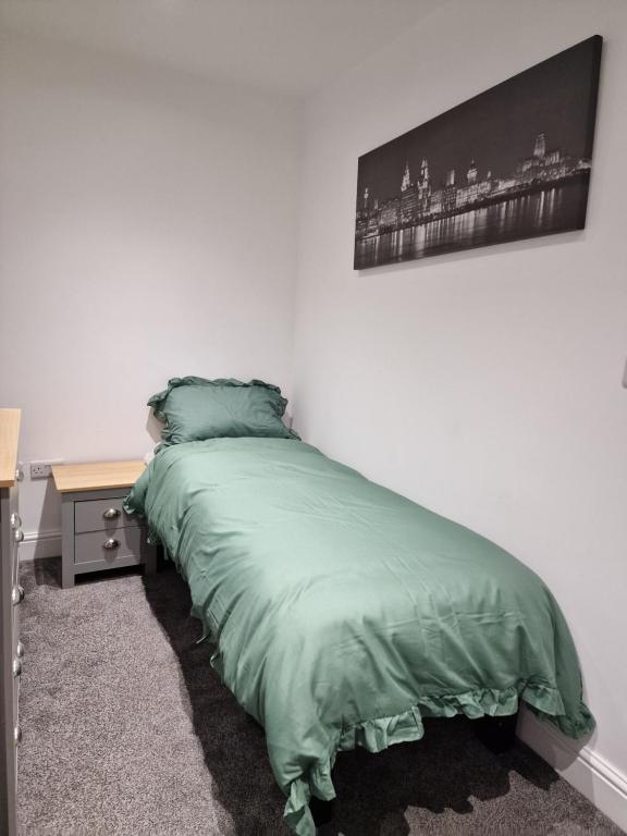 a bed with a green comforter in a bedroom at Beautiful Single Bedroom in Liverpool