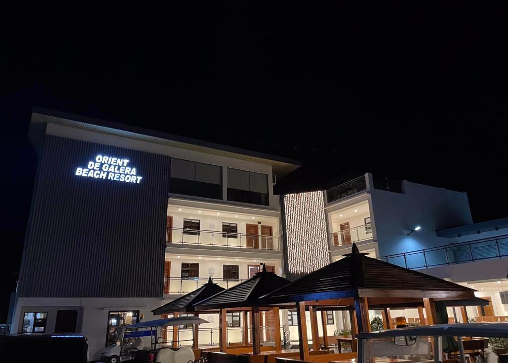 Orient De Galera Beach Resort في Balatero: مبنى أمامه لافتة مضاءة