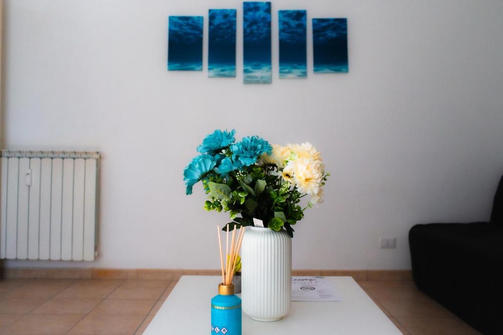 un jarrón blanco con flores en una mesa en MareSole Apartment, en Lido di Ostia