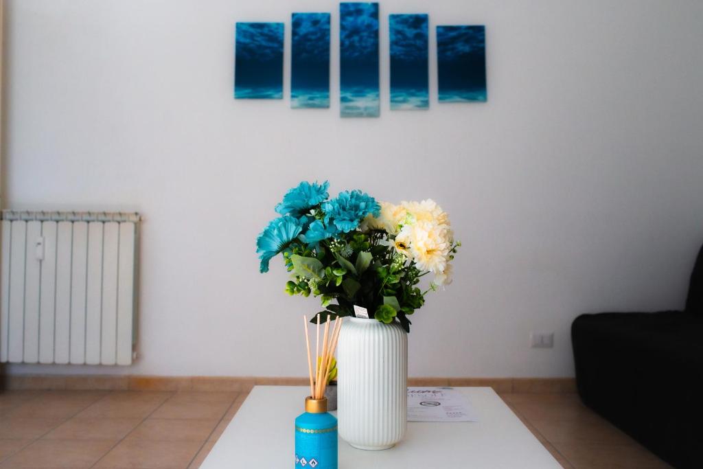 a white vase with flowers on a table at MareSole Apartment in Lido di Ostia
