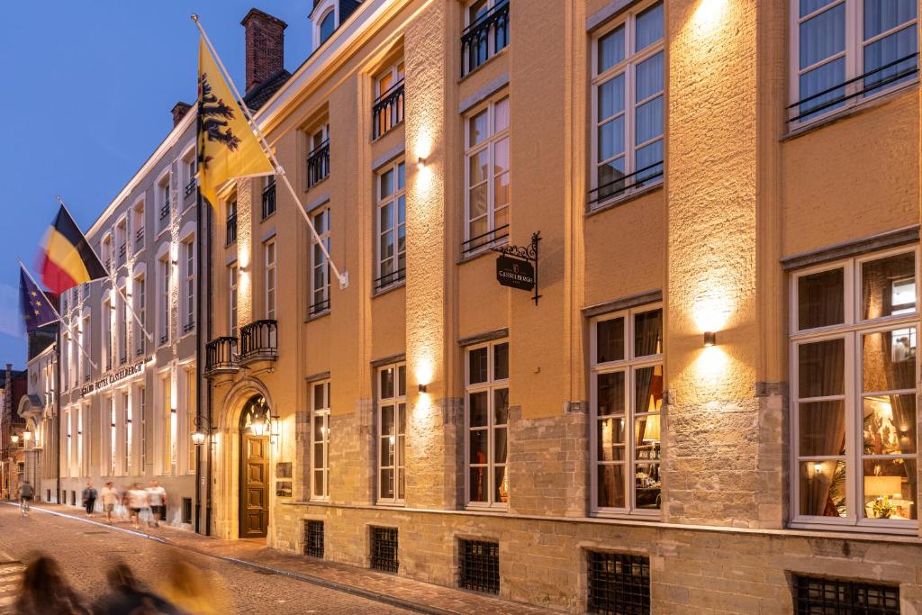 a building with flags on a street at night at Grand Hotel Casselbergh in Bruges