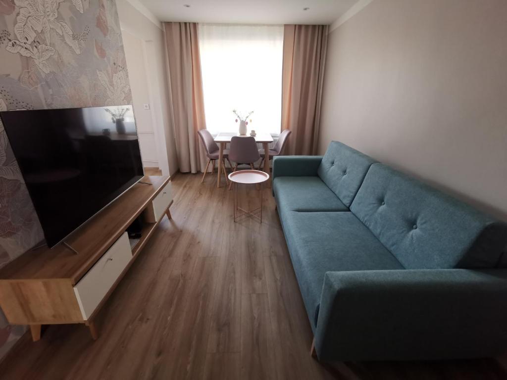 a living room with a blue couch and a television at Apartament Parkowe Love in Chorzów