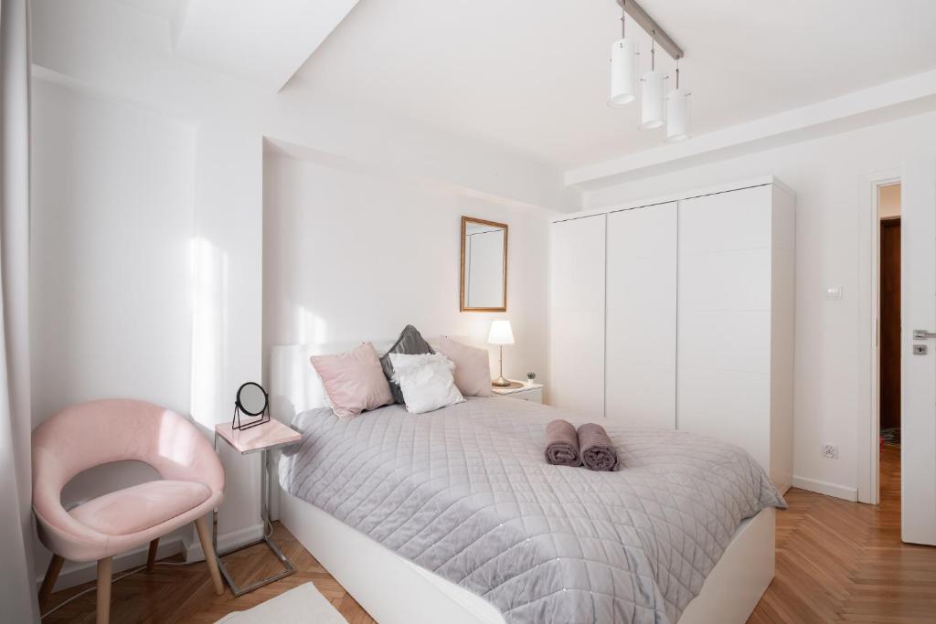 a white bedroom with a pink chair and a bed at GA- One Bedroom Apartment -Old Town - Anielewicza in Warsaw