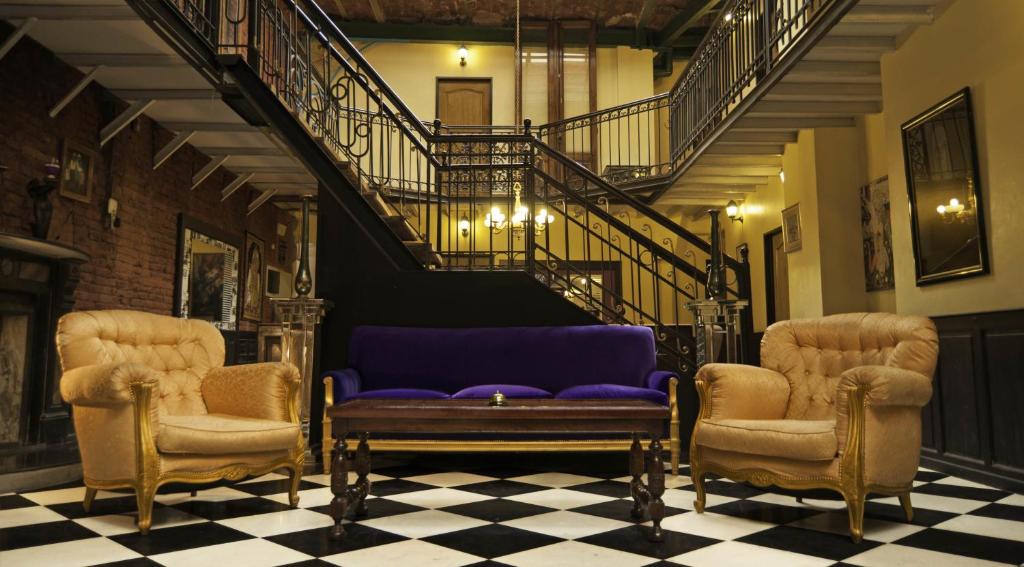 uma sala de estar com um sofá roxo e duas cadeiras em DEL900 Hotel Boutique em Buenos Aires