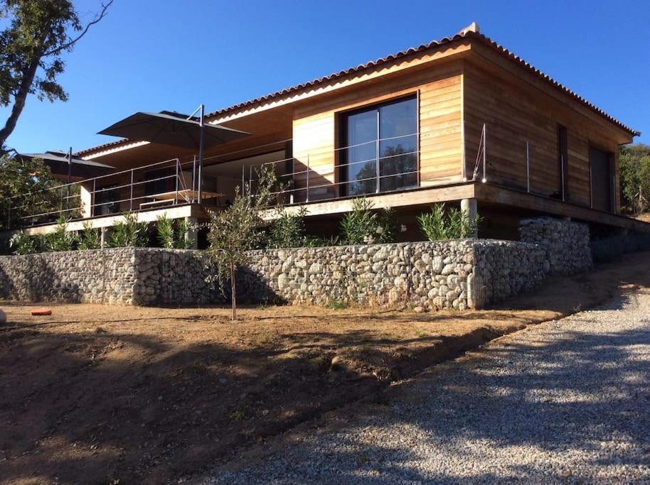 une maison avec un mur en pierre devant elle dans l'établissement Villa contemporaine à 500 mètres de la plage !, à Calcatoggio