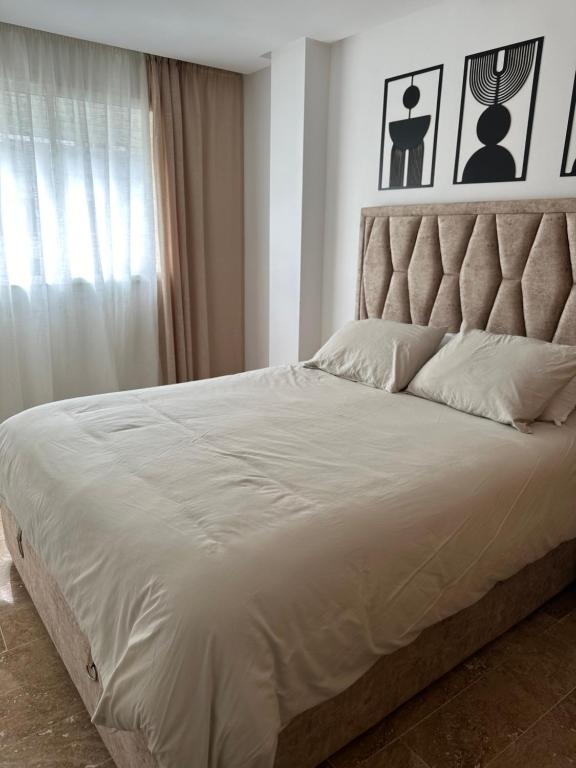 a bedroom with a large white bed with a headboard at Cosy appartement avec piscine à Mohamedia in Mohammedia