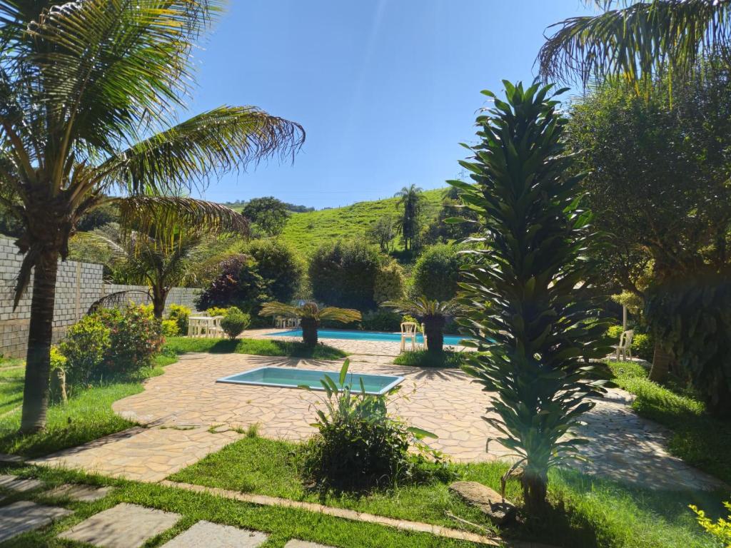 een zwembad in een tuin met palmbomen bij Sítio da Fabi in Brumadinho
