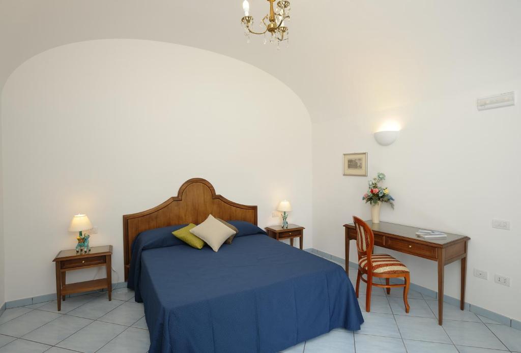 a bedroom with a blue bed with a desk and a chair at Il Ducato Di Ravello in Ravello