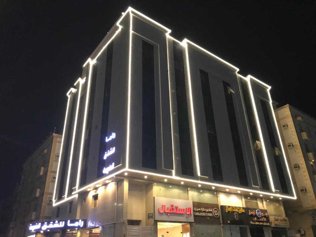 a tall building with lights on it at night at راما للاجنحة الفندقية in Jeddah