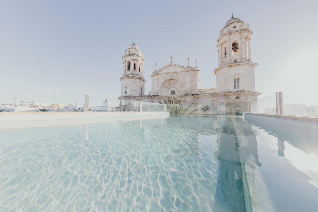 una iglesia con una piscina de agua delante en Boutique Hotel OLOM - Only Adults recommended, en Cádiz