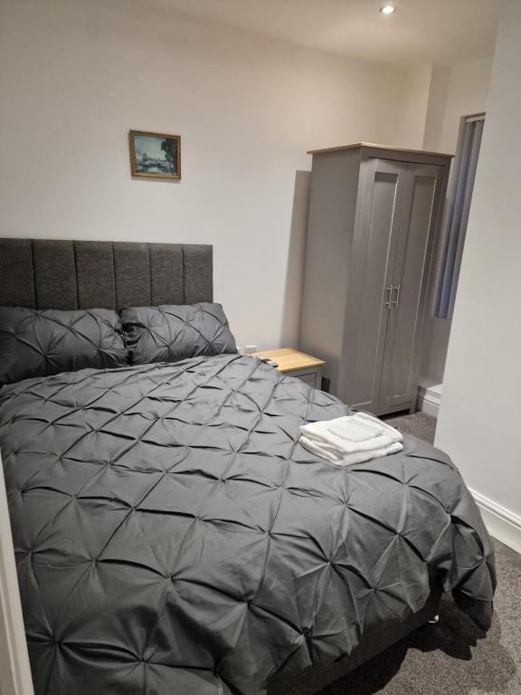 a bedroom with a bed with a gray comforter at Spacious Double Bedroom in Liverpool