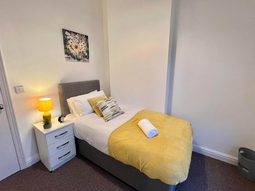 een kleine slaapkamer met een bed met een gele deken bij Spacious 5-bed house in Coventry by Seeka Stay, Ideal for business, Sleeps 7! in Exhall